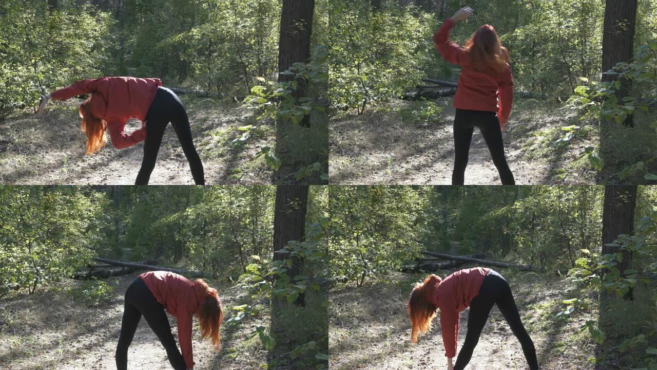 红头发的年轻女孩在公园做运动。在阳光明媚的秋天，她穿着红色外套在空地上做体操。后视图。