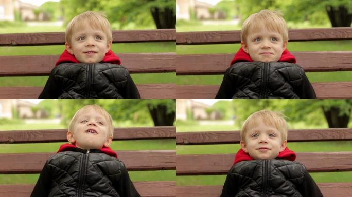 在公园的长凳上，一个欢快的笑男孩的特写肖像。