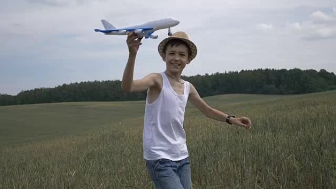 戴着草帽的快乐男孩梦想家手持飞机穿越田野