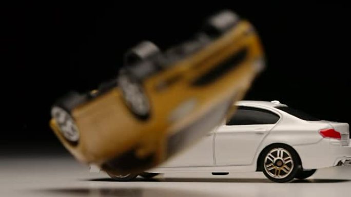 慢动作: 黄色玩具车跳上白色玩具车，然后翻车