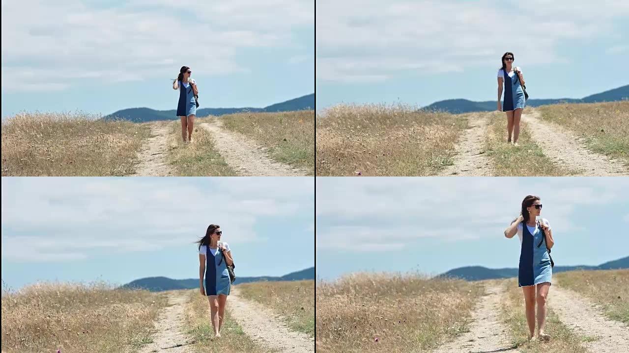 迷人的女性旅行者享受走在令人惊叹的夏季景观的田野长镜头