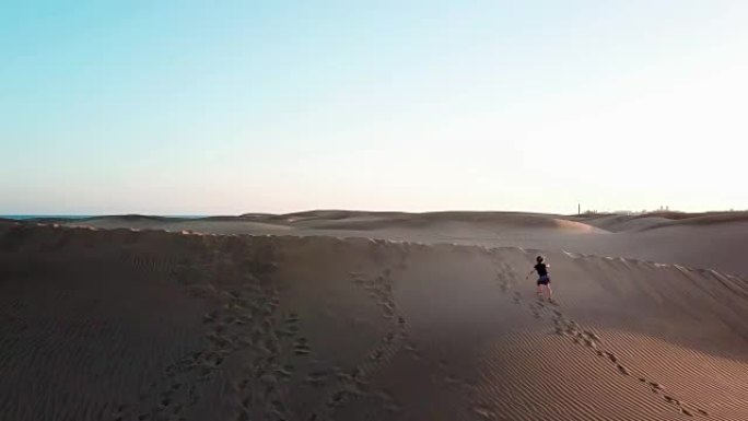 可爱的小女孩正在沙漠中沙丘上攀爬，背后是美丽的兰西角。假期快乐的小孩在沙漠里玩沙子。大加那利岛