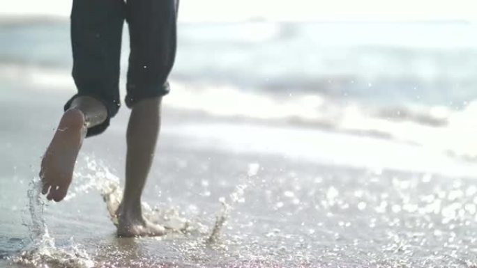 快乐男孩沿着海边在海滩上奔跑。慢动作