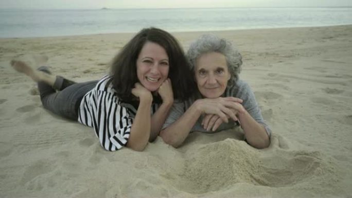 快乐的成年女性躺在沙滩上玩得开心
