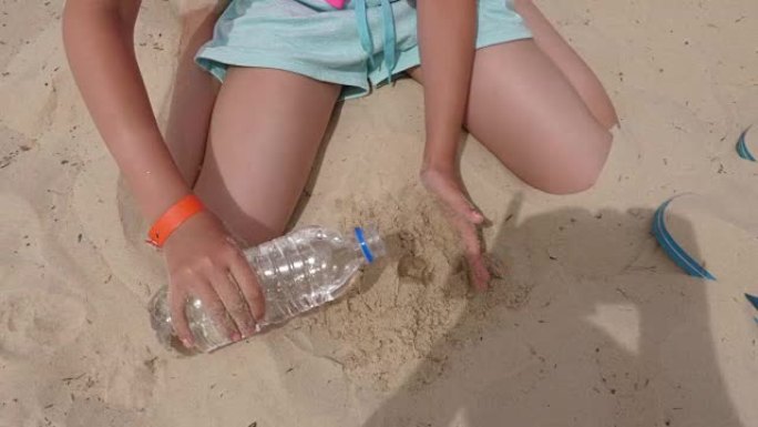 女孩的手在夏天的海滩上用沙子和水做沙球