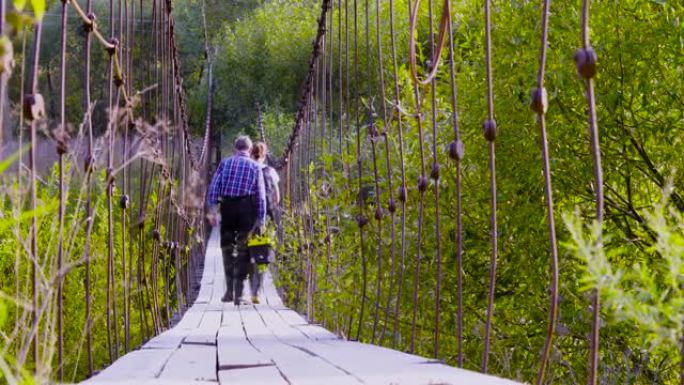 两名穿着高胶靴的科学家生态学家在吊桥上行走