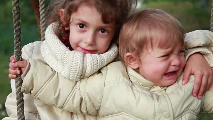 小女孩拥抱她的妹妹，但她开始哭