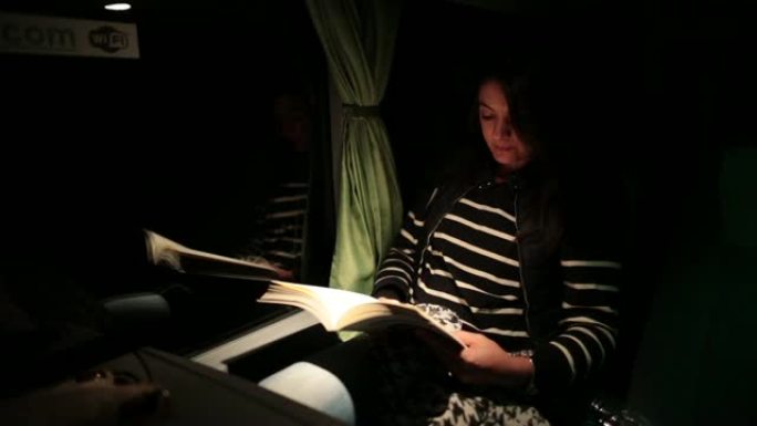 乘客妇女晚上在公共汽车上读书