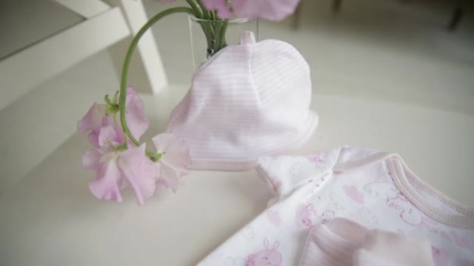 粉红色花朵背景下新生女孩的婴儿服装特写