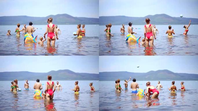 一群快乐的人在水中跳跃和打沙滩排球。一群年轻人在海滩上。4K (UHD