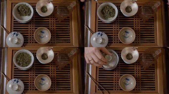 师傅在盖湾用茶壶倒热水，茶几上有绿茶