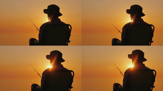 后视图-一个男人坐在海边，用钓鱼竿钓鱼