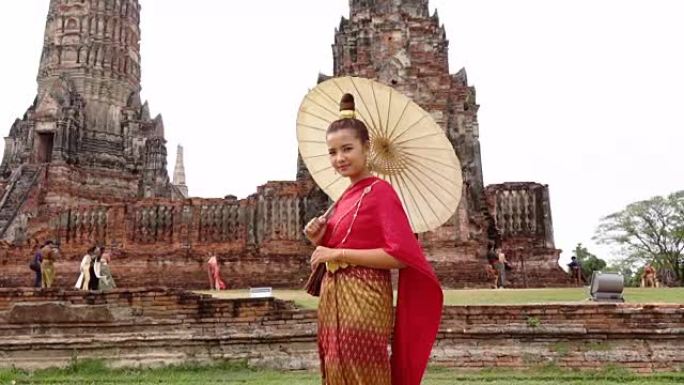 穿着泰国民族礼服的泰国年轻女子在阿育泰的老庙中行走