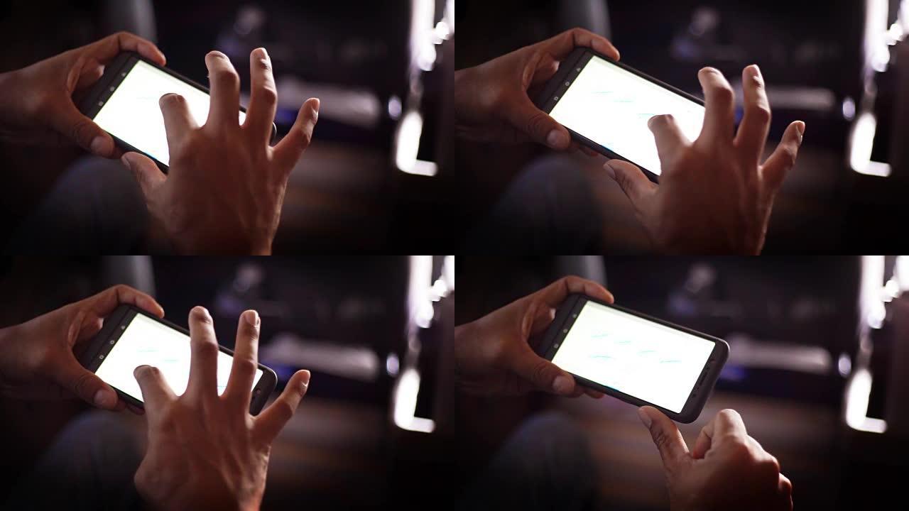 男人的手在晚上使用智能手机。
