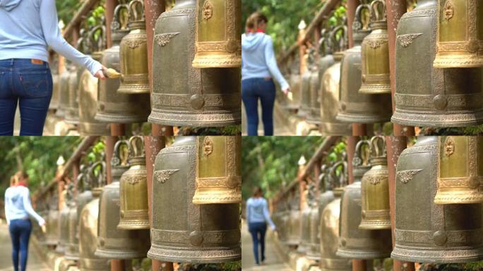 年轻女子在泰国寺庙里为运气敲响大钟
