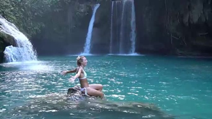 瀑布中的年轻女子玩水，慢动作视频。人们旅行乐趣享受理念。在菲律宾拍摄