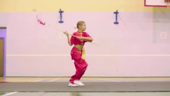 穿着红色逸夫衣服的年轻女孩做千行形式练习中国功夫太极拳。