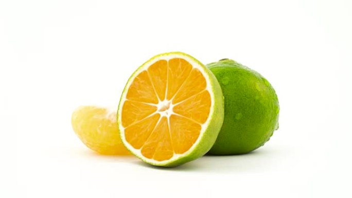 一个完整的半个绿色橘子水果，带有水滴。绿色普通话切片旋转。孤立在白色背景上。特写。宏观。