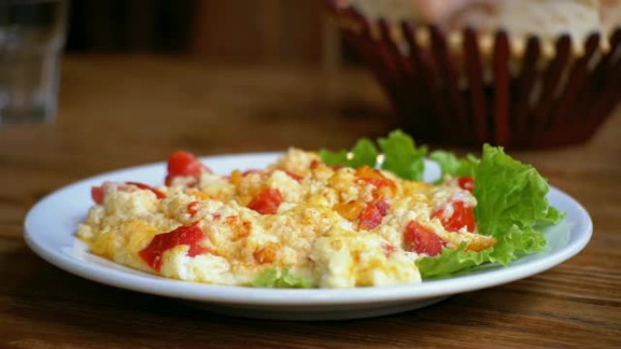 一盘格鲁吉亚煎蛋卷，西红柿、奶酪和香草放在餐厅的木桌上。