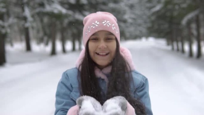 一个心情愉快的女孩在冬天的森林里从手中吹雪