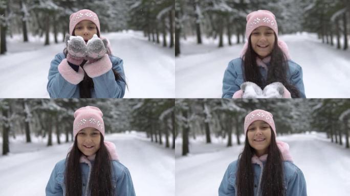 一个心情愉快的女孩在冬天的森林里从手中吹雪