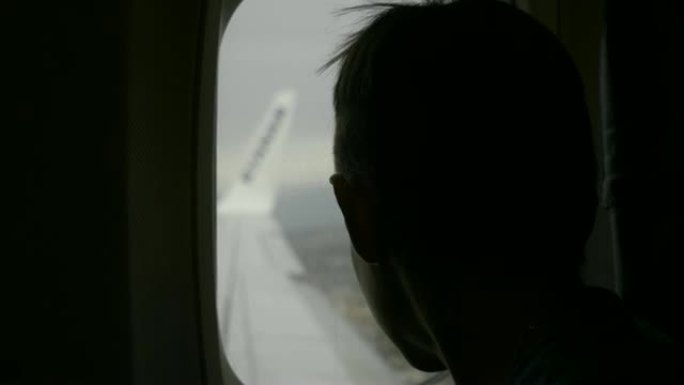 男孩坐飞机，看着窗外