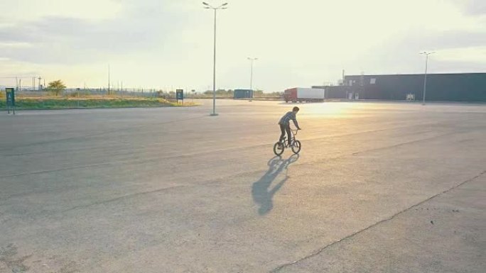 在城市街道上的沥青表面，年轻骑手在bmx自行车上表演技巧的飞行视图