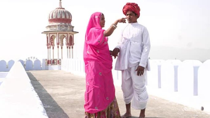 美丽的新娘和新郎在印度拉贾斯坦邦普什卡的屋顶上悠闲地约会