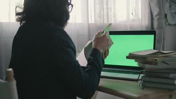 年轻女子在家中使用带有绿色屏幕的笔记本电脑