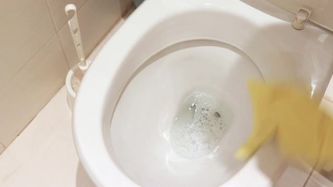 女人用手擦拭黄色橡胶手套清洁肮脏的马桶。家政、洗涤和清洁浴室概念