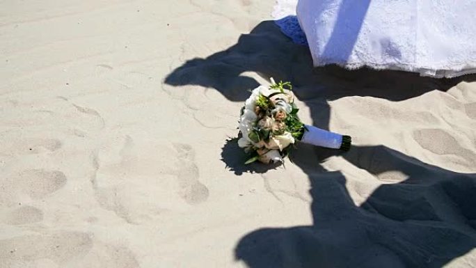 夏天，沙漠，在沙子的背景下，婚礼花束躺在上面，阴影，穿着婚纱的人的轮廓，携手共进