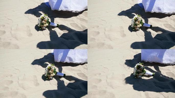 夏天，沙漠，在沙子的背景下，婚礼花束躺在上面，阴影，穿着婚纱的人的轮廓，携手共进