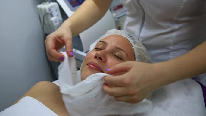 美容师用湿餐巾纸清洁女人的脸的特写镜头。