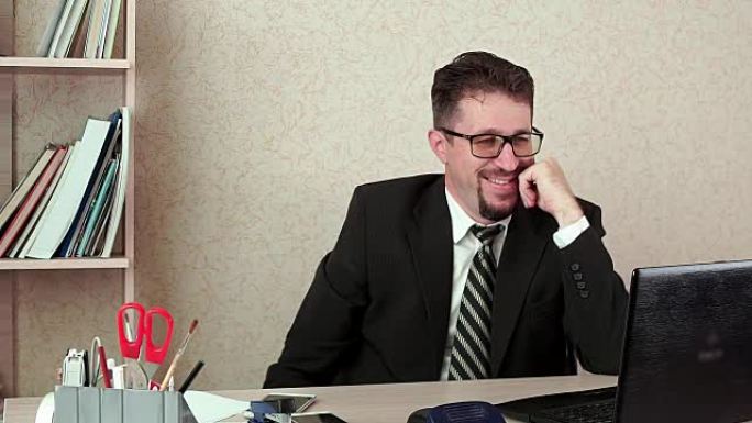 办公室经理男人，留着胡须和眼镜，通过笔记本电脑中的视频链接交谈。
