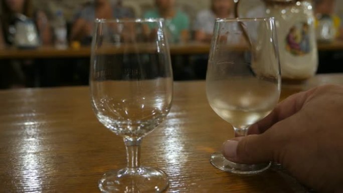 在品酒室品酒。在克里米亚酿酒厂周围游览。巴卡利站在桌子上。将酒倒入玻璃盘中。侍酒师把手伸向酒杯。阳光