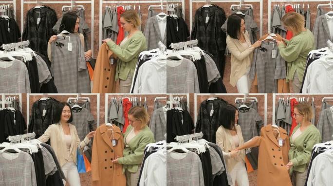年轻女子在服装店选择一件衣服，并与她的朋友咨询。在镜子里试穿衣服。布鲁内特女孩打算买一件衣服，和金发