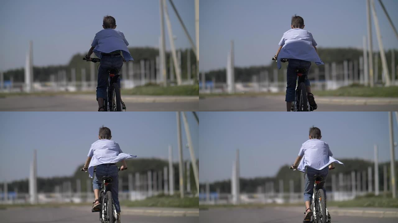 男孩正在骑自行车，后视图，衬衫在风中发展，慢动作