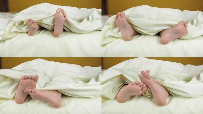 毯子下孩子的脚。床上的孩子