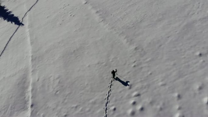 一个孤独的游客在山林里穿过雪地。旅行者在冬天白雪覆盖的森林里鸟瞰。在四轴飞行器上射击。