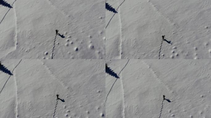 一个孤独的游客在山林里穿过雪地。旅行者在冬天白雪覆盖的森林里鸟瞰。在四轴飞行器上射击。