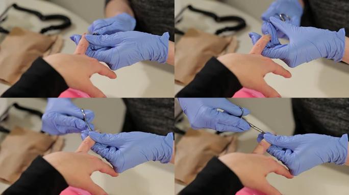 美甲师用指甲剪刀去除女性指甲上的角质层。