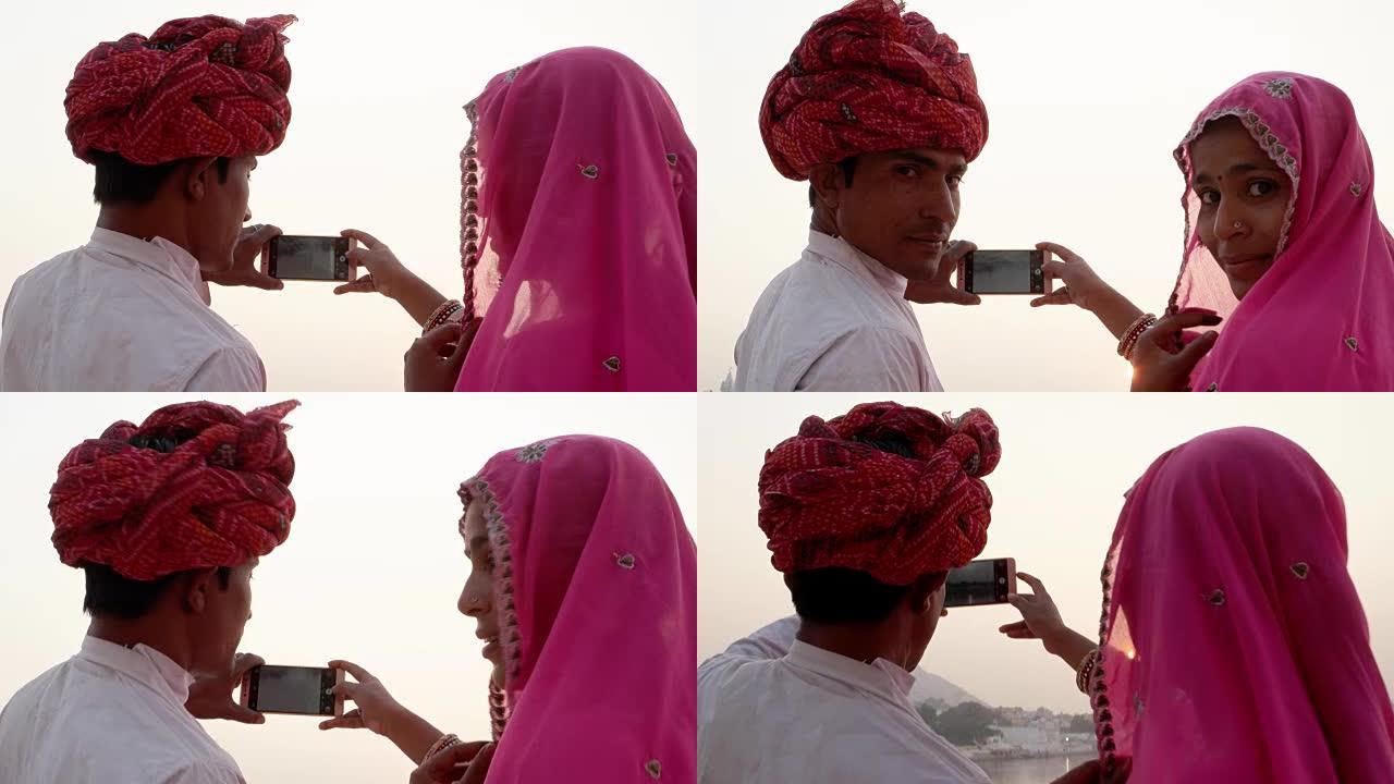 印度夫妇在拉贾斯坦邦圣普什卡湖回头看相机并拍摄日落照片