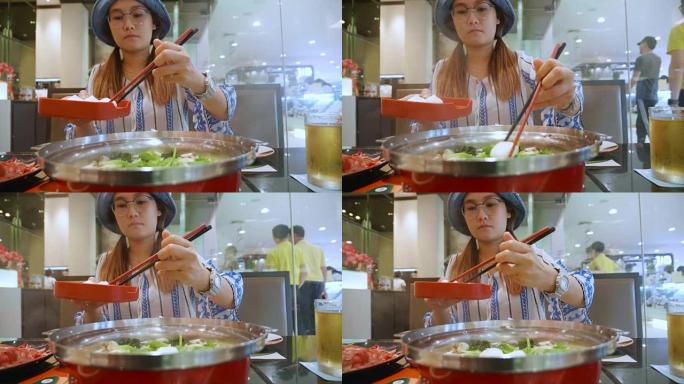 年轻的亚洲女子与火锅寿喜烧泰国风格。