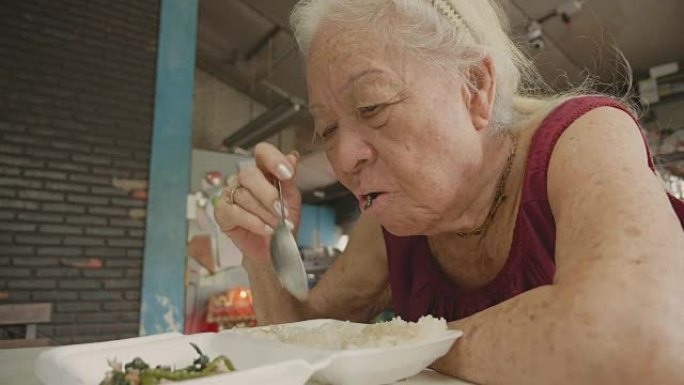 资深亚洲女性在家吃食物。
