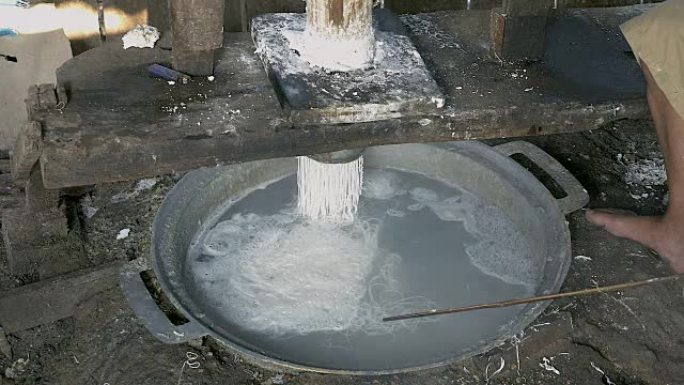 关闭一个男人压米面团; 米粉直接在沸水中煮熟