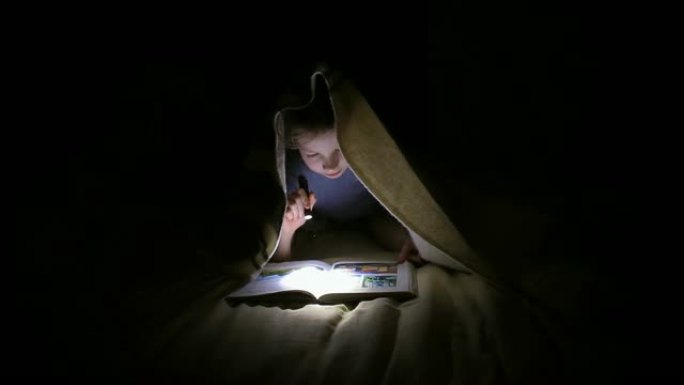 小女孩晚上在黑暗的房间里用手电筒在毯子下看书