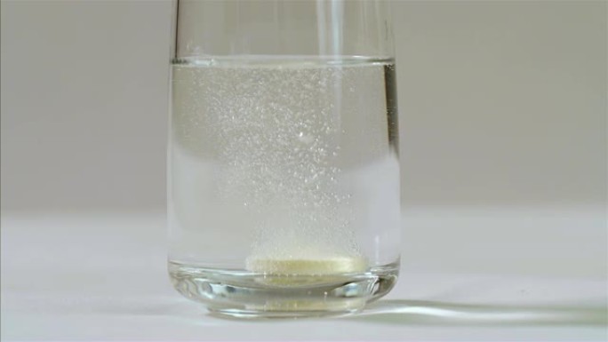 冒泡维生素c片剂在黑色背景上的一杯水中气泡，75 fps慢动作