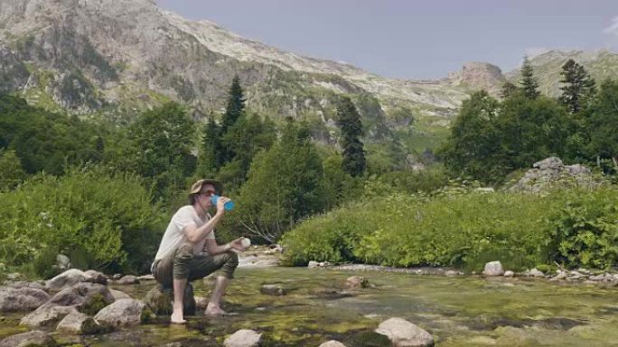 徒步旅行者在夏季旅行中从山溪中取水