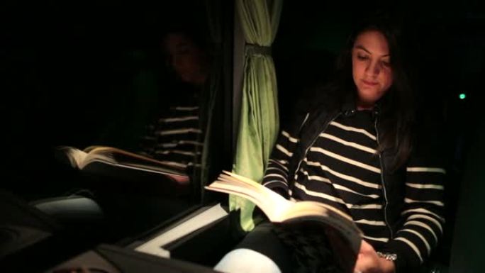 乘客妇女晚上在公共汽车上读书