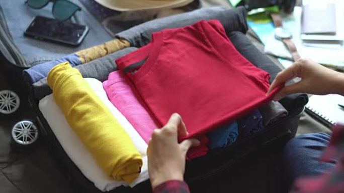 女人把衣服放在床上的手提箱里，为新的旅程做准备。